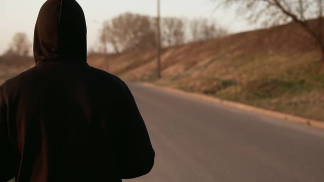 Lone runner at sunset outdoors in black hooded sweater. Slow motion