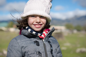 Close-up of a little girl with wool cap and scarf in the field