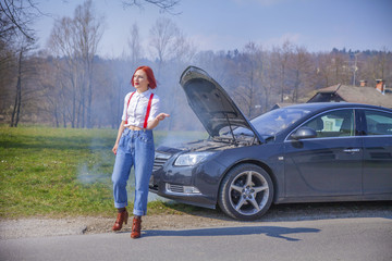 A young woman is waiting for someone how is going to fix her car that broke down.