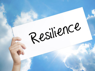 Resilience Sign on white paper. Man Hand Holding Paper with text. Isolated on sky background