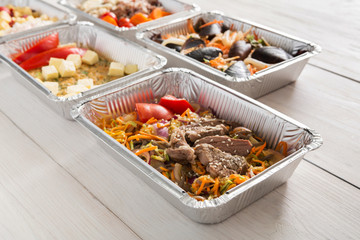 Healthy food take away in foil boxes on wood background