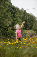 Naklejka na ściany i meble Little girl playing on the meadow