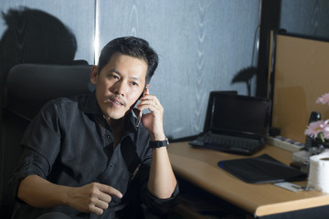 businessman working on laptop computer, talking on mobile phone.