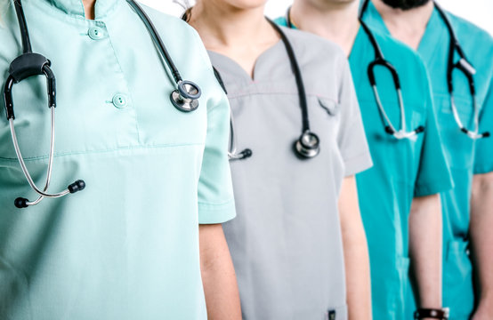 Doctors dressed in surgical suits stand in a row. On the necks of doctors hang black phonendoscopes.