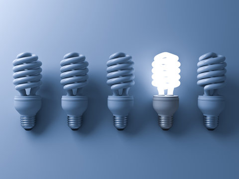 Energy saving light bulb , one glowing compact fluorescent lightbulb standing out from unlit light bulbs on blue background , individuality and different creative idea concepts . 3D rendering.