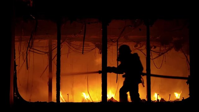 Brave fireman inside burning building. Fire extinguishing, fire brigade inside burning premises. House destroyed by fire