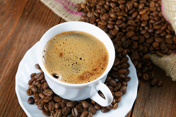 Cup with coffee on the table next to coffee beans