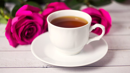 Romantic St Valentine's or vedding setting with tea cup and red roses