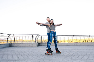 Fototapeta premium Beautiful sweet couple riding on roller skates holding hands