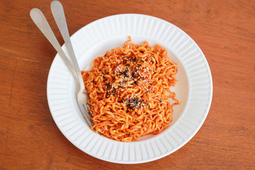 Spicy noodles sprinkle sesame seeds and seaweed on a wooden background.