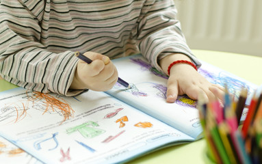 The child draws with pencils