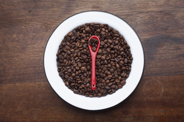 Plate with coffee beans over  wood background
