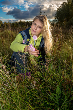 Pretty blonde woman among grass in the summer field