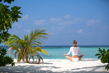Meditation Yoga woman meditating at serene tropical beach. Girl relaxing in lotus pose in calm zen moment at ocean water