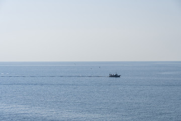 Seascape with small fishing boat sailing on calm sea
