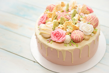 Pink cake with flowers and cupcakes on a white plate