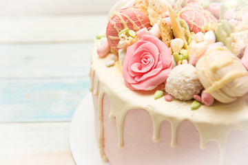 Pink cake with flowers and cupcakes on a white plate
