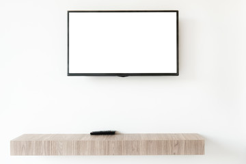 Mock up flat tv screen with remote panel on wwden shelf in living room at home.