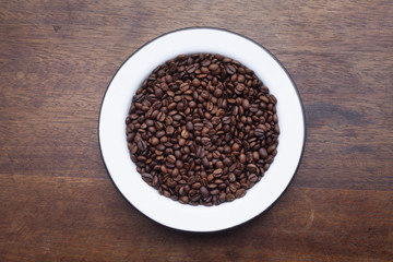 Plate with coffee beans over wooden background