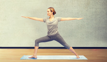 woman making yoga warrior pose on mat