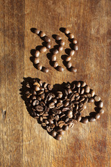 Cup made of coffee beans over wood background
