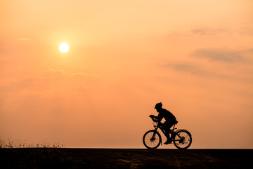 Naklejka na ściany i meble Silhouette of cyclist on sunset background