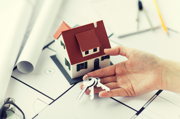 close up of hand with house keys and blueprint