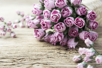 Pink paper rose in weave basket on old wood