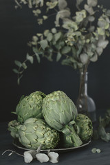 Obraz premium Fresh green artichokes on a table on a dark background. 