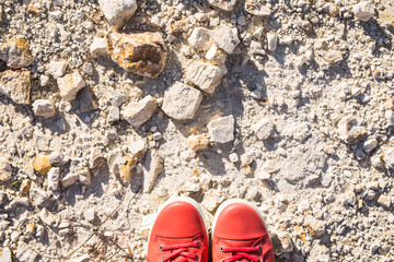 Feet in casual pink shoes on the stone background