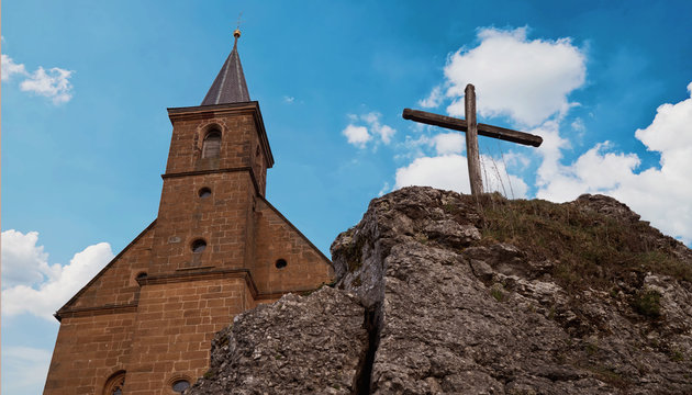 View on a church and a cross in front of a wonderful clouded sky - slightly sepia toned