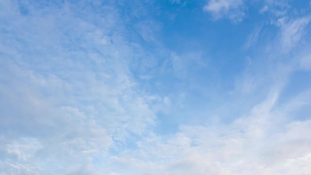 Time-lapse still of blue sky and clouds, showing a close-up view of the fluffy white formations drifting across a clear, bright background