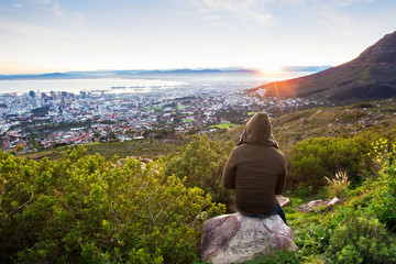 Faceless Hiker looking at beautiful view of sunrise over city