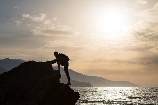 Climbing hiking silhouette in mountains and ocean