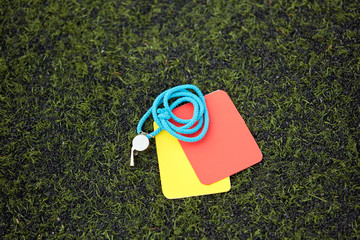 referee whistle and caution cards on soccer field