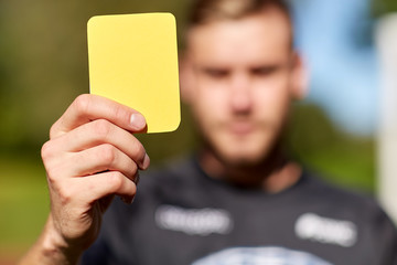 referee on football field showing yellow card
