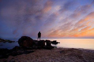man waching calm beautiful sea sunrise with colorful dramatic clouds