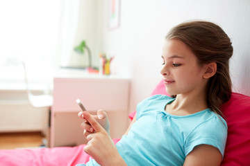 smiling girl texting on smartphone at home