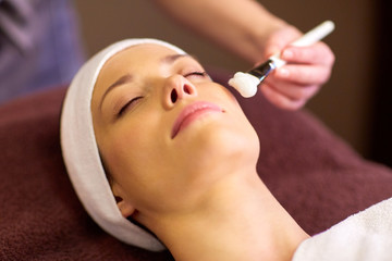 Naklejka premium beautician applying facial mask to woman at spa