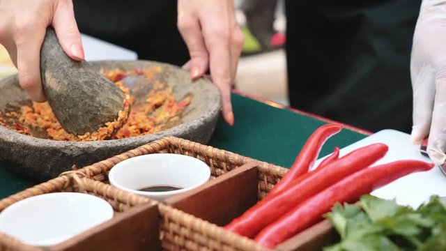 Close up of woman grinding onion and chili in balinese mortar and pestle, cooking class. Shot with Sony a7s on slider