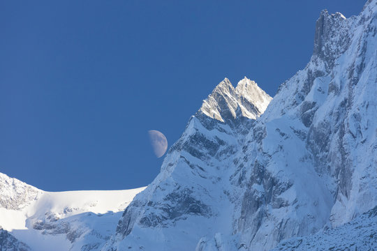 Blue sky and moon on the snowy ridges of the high peaks, Soglio, Bregaglia Valley, Canton of Graubunden