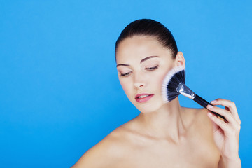Portrait d'une femme utilisant une brosse de maquillage sur le visage