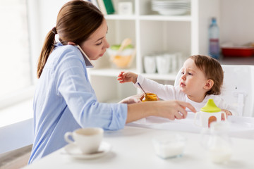 Obraz na płótnie Canvas mother with smartphone feeding baby at home