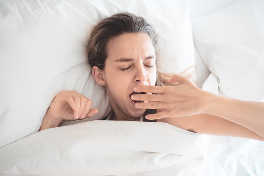 Donna sbadiglia a letto, assonnata