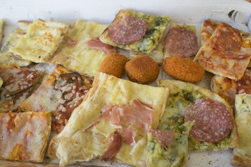 variety of types of pizza cut in pieces and arancine