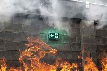Gordijnen Nooduitgang op de stenen muur met vuur en rook © irontrybex