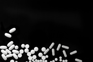 Bunch of various white pills on black background