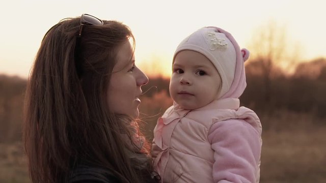 Mom plays with daughter and having fun against of sunset sky. Slow motion shot