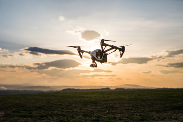 quadrocopter drone with remote control. Dark silhouette against colorfull sunset.