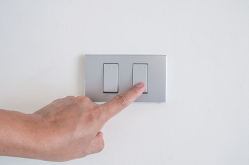 Unidentified man hand with finger on light switch turn on turn off  lights.  Save the earth concept.